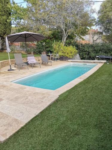une piscine avec deux chaises et un parasol dans l'établissement Haut de villa VERMEER, à Six-Fours-les-Plages