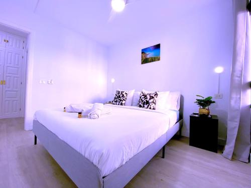 a bedroom with a large bed with white sheets at Tropicalidays Sunset Palm in Costa Del Silencio
