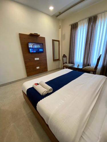 a bedroom with a large bed with a tv on the wall at The Woodlark !! Managed by Sidham Hospitality !! in Chandīgarh