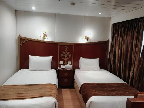 two beds in a hotel room with two at Nile cruise, Luxor, Aswan, Floating hotel Alhambra A F in Aḑ Ḑab‘īyah