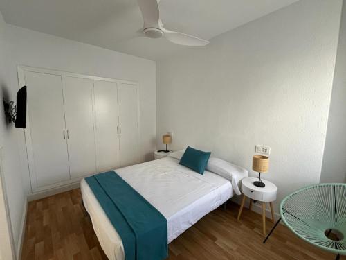 a white bedroom with a bed and a table at Kione Las Margaritas in Alcossebre