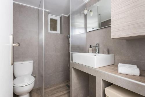 um banheiro com uma pia branca e um vaso sanitário em City Nexus Family 2BD residence Kolonos, Athens em Atenas