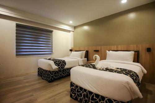 two beds in a hotel room with two swans on them at Forest Crest Nature Hotel and Resort Powered by ASTON in Nasugbu