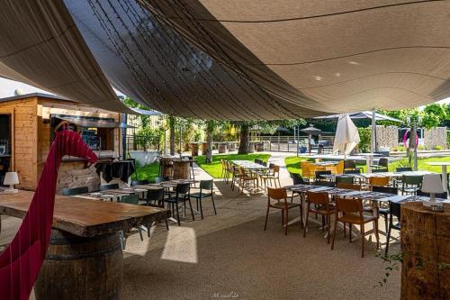 an outdoor patio with tables and chairs and tables and tablesearcher at Hôtel Karène in Saint-Paul-lès-Romans