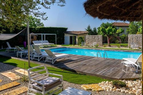una piscina con sedie e una terrazza in legno accanto alla piscina di Hôtel Karène a Saint-Paul-lès-Romans
