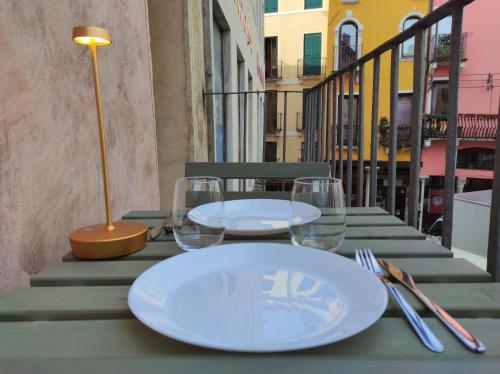 een tafel met borden en wijnglazen op een balkon bij CASA MARGHERITA Basilica view & Terrace in Vicenza