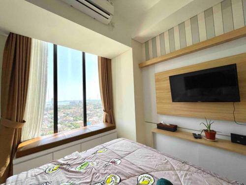 een slaapkamer met een bed en een flatscreen-tv bij Aesthetic Studio Unit in Bluhen Tower in Batam Center