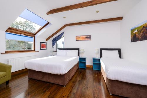 2 Betten in einem Zimmer mit 2 Fenstern in der Unterkunft An Capall Dubh B&B Dingle in Dingle