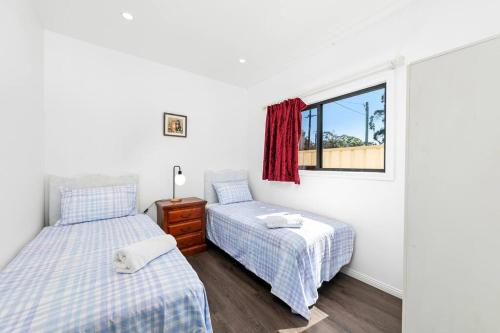 1 dormitorio con 2 camas y ventana en 4Bed Modern Oasis by Train Station, en Wyong