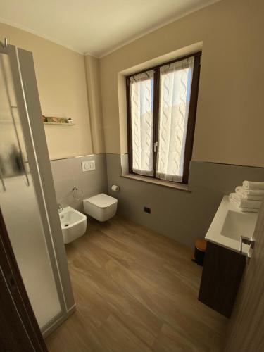 a bathroom with a toilet and a sink and a window at Casa Rubbo - Appartamento in collina 'Monviso' in Alba