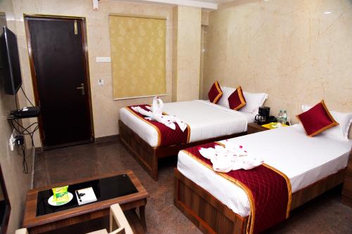 a hotel room with two beds and a television at Sri Vishnu Residency in Sriperumbudur