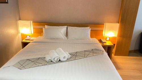 a bedroom with a white bed with two lamps at Buritel Hotel in Buriram