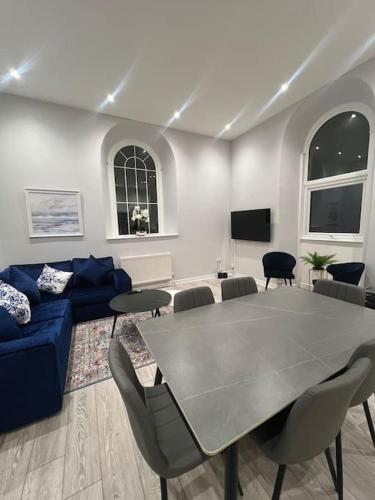 ein Wohnzimmer mit einem Tisch und einem blauen Sofa in der Unterkunft Welsh Getaway Apartment - Town Centre in Merthyr Tydfil