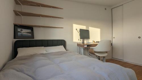Schlafzimmer mit einem Bett und einem Schreibtisch mit einem Computer in der Unterkunft Appartement lumineux et cosy avec balcon - 3P in Les Lilas