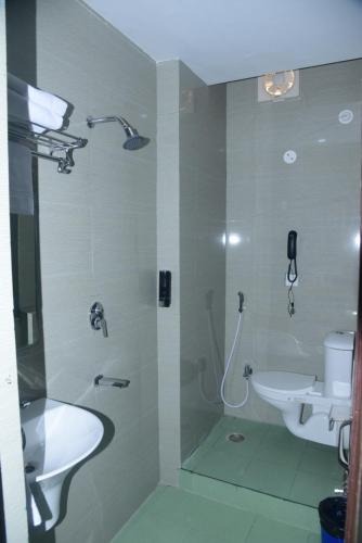 ein Bad mit einer Dusche, einem Waschbecken und einem WC in der Unterkunft Hotel Gridhakuta International in Rajgir