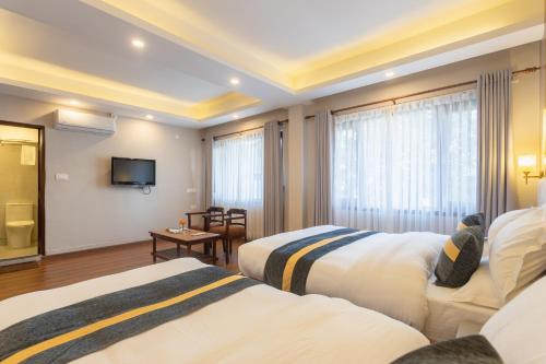 a hotel room with two beds and a television at Aawas Boutique Hotel in Kathmandu