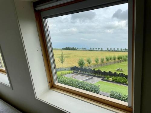 een raam in een kamer met uitzicht op een veld bij Vakantiewoningen de Schelp in Renesse