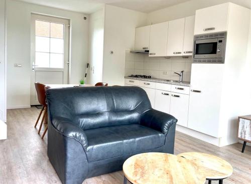 a living room with a leather chair and a kitchen at Vakantiewoningen de Schelp in Renesse