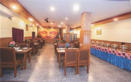 ein Restaurant mit Tischen und Stühlen und einem Gesicht an der Wand in der Unterkunft Sun Star International Hotel 24/7 in Siddharthanagar