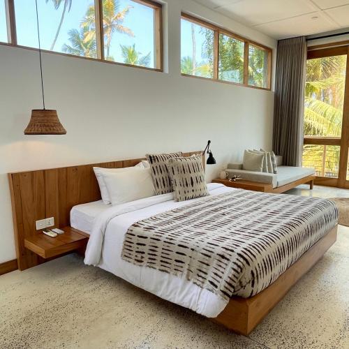 a bedroom with a large bed and windows at La Playa Beach Club in Hiriketiya