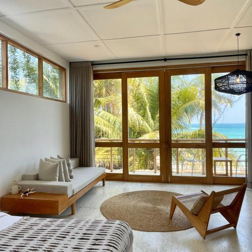 a bedroom with a bed and a large window at La Playa Beach Club in Hiriketiya