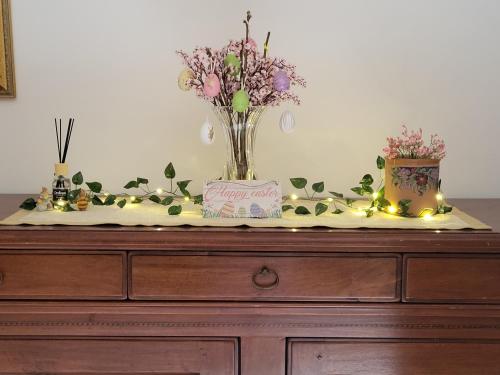 a dresser with a vase of flowers and lights on it at Appartamento Beatrice e Vioris in Pila