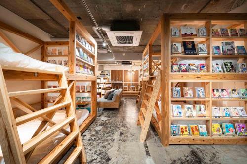 a room with several bunk beds and books at MANGA ART HOTEL, BAKUROCHO in Tokyo