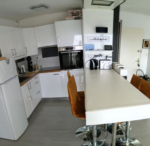 une cuisine avec des placards blancs et un comptoir blanc dans l'établissement Elégant Appartement, au Barcarès