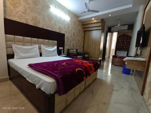 um quarto com uma cama grande e um cobertor roxo em Sardar House em Nova Deli