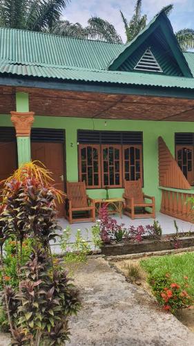 a green house with benches in front of it at Wisma Batu Mandi in Bukit Lawang