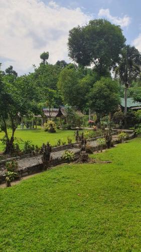 a park with green grass and trees and a building at Wisma Batu Mandi in Bukit Lawang