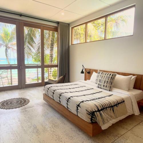 1 dormitorio con 1 cama y ventanas grandes en La Playa Beach Club, en Hiriketiya