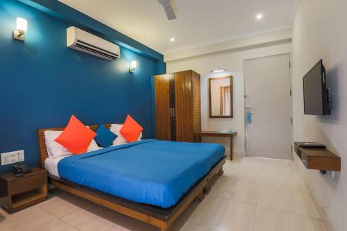 een blauwe slaapkamer met een bed met oranje kussens bij Hotel Wedlock 39 in Gurgaon