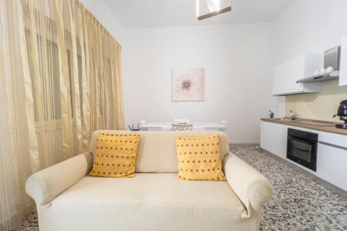 Casa vacanze Cetto e Vera في غالاتينا: أريكة بيضاء مع وسادتين صفراء في مطبخ