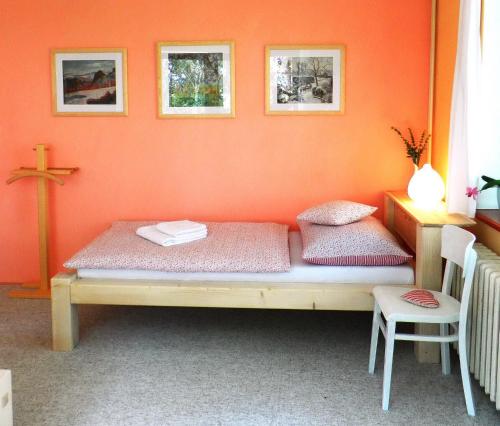 a bed in a room with an orange wall at Penzion Bor in Náchod
