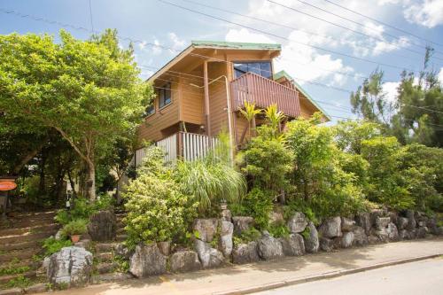 a house with a stone wall in front of a house at 木の温かみ溢れる自然の中のログハウス～Cottage HIBISCUS～ in Inbu