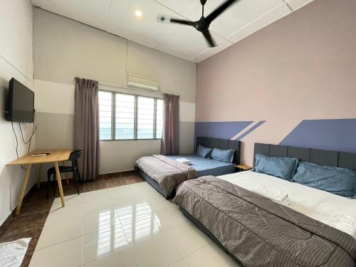 een slaapkamer met 2 bedden, een bureau en een televisie bij Muslim Homestay Teluk Intan ( Hotel Style Room ) by Mr Homestay in Teluk Intan