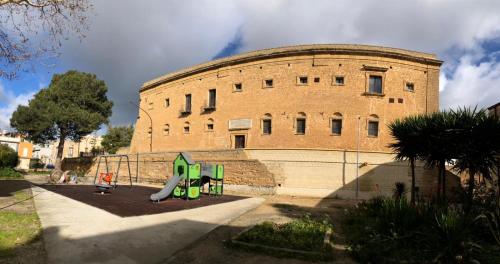a large brick building with a playground in front of it at Camagna Country House in Santa Ninfa