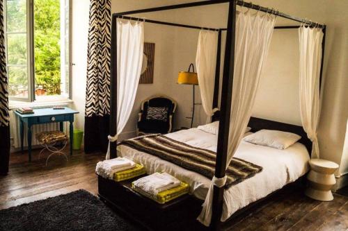 1 dormitorio con cama con dosel y silla en Demeure de 11 chambres avec piscine partagee et wifi a Pech Luna, en Pech-Luna
