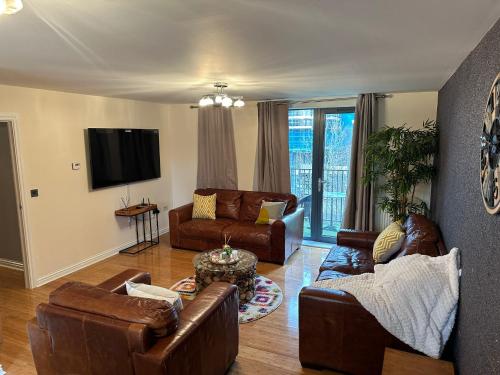 a living room with leather furniture and a flat screen tv at Long term cozy flat in Hendon