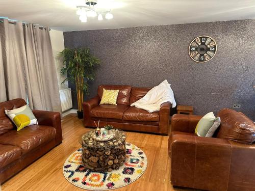 a living room with leather furniture and a clock on the wall at Long term cozy flat in Hendon