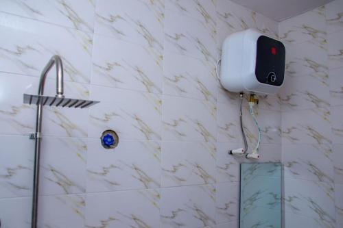 uma casa de banho com um chuveiro e um dispensador de sabonete na parede em Bellevue Apartment em Lagos