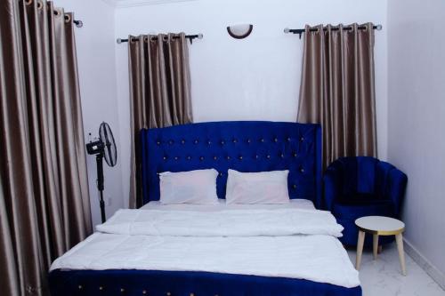 uma cama azul com uma cabeceira de cama azul e uma cadeira em Bellevue Apartment em Lagos
