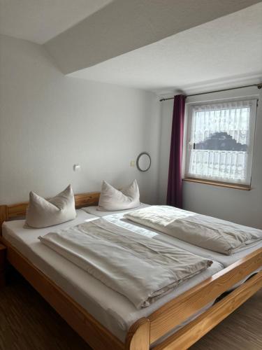 a bedroom with a large bed with white sheets and a window at Hotel-Restaurant Cafe Caro in Carolinensiel