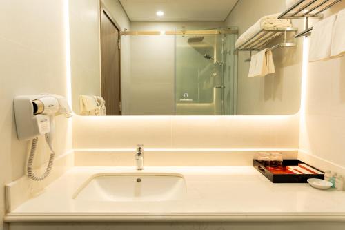 W białej łazience znajduje się umywalka i lustro. w obiekcie Capital Garden Hotel w mieście Hanoi