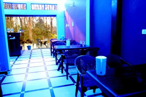 un restaurante con paredes azules, mesas y sillas en Jolly Hill Stay en Rāni Pokhri