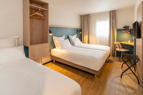 a hotel room with two beds and a desk at Le Carline, Sure Hotel Collection by Best Western in Caen