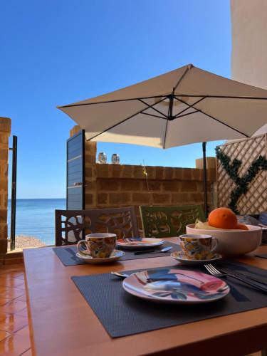 a table with plates of food and an umbrella at Gioia di Mare in Marzamemi