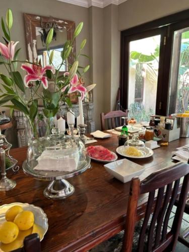 a wooden table with a vase of flowers on it at The Lemon Tree Self- Catering in Johannesburg