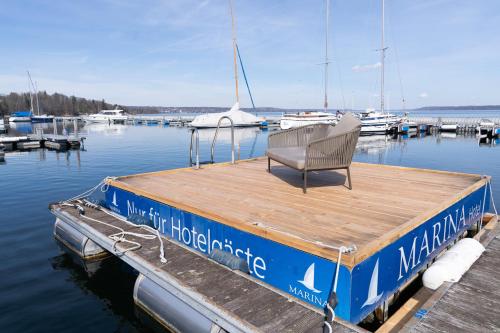a boat with a chair sitting on the dock at Marina Hotel am Starnberger See in Bernried